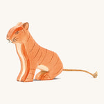 A wooden sitting Ostheimer tiger figure on a cream background.