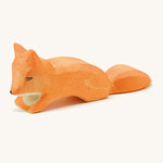 A small wooden Ostheimer creepng fox figure on a cream background.