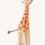 A small wooden Ostheimer figure with its head held high on a cream background.