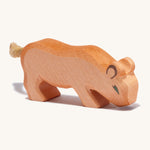 A small wooden Ostheimer lion with its head low on a cream background.