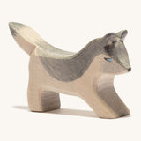 A small wooden Ostheimer wolf playing, on a cream background.
