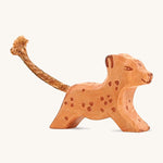 A small running wooden Ostheimer leopard figure on a cream background.