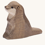 A small wooden Ostheimer sea otter figure on a cream background.