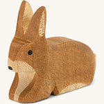 A small brown spotted sitting Ostheimer rabbit figure on a cream background.