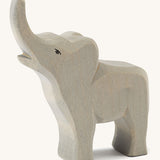A small wooden trumpeting Ostheimer figure on a cream background.