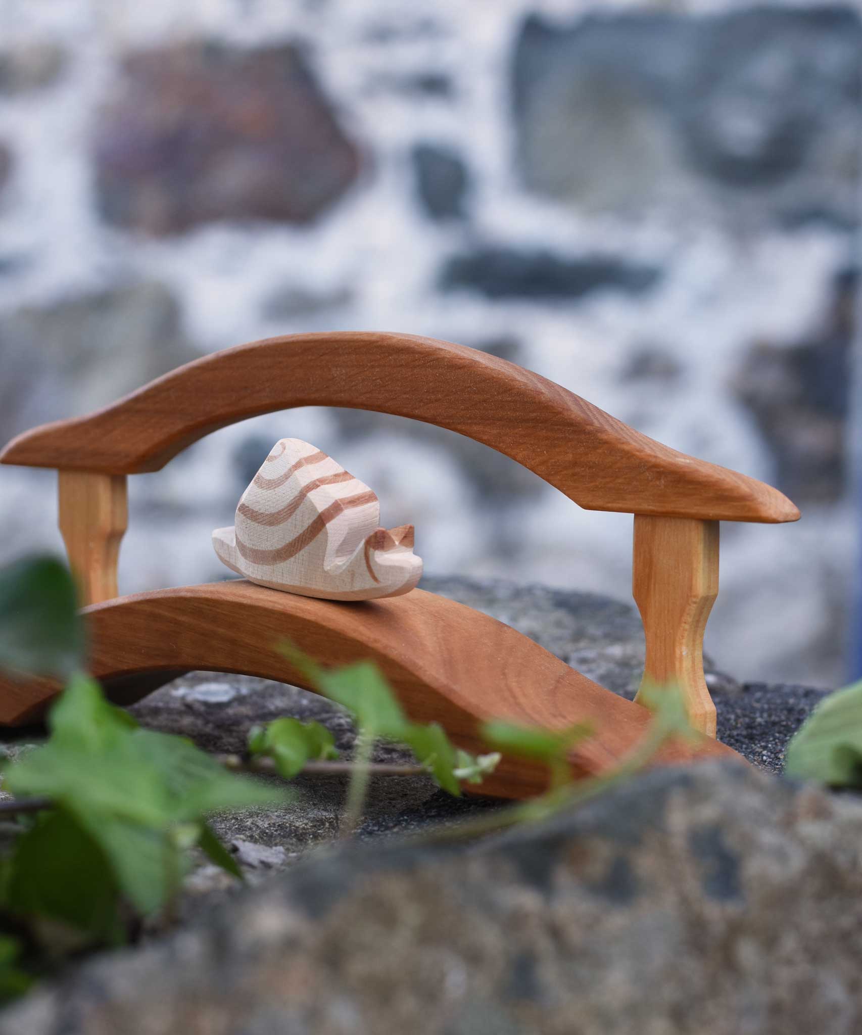An Ostheimer wooden snail figure placed on the Ostheimer wooden bridge with railing. These wooden toys are part of a wide range of Ostheimer figures available at Babipur.