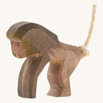 A wooden standing Ostheimer baboon figure on a cream background.