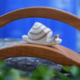 A close up of the Ostheimer snail figure on a wooden bridge. The wooden snail figure has a cream white coloured base with brown detailing.