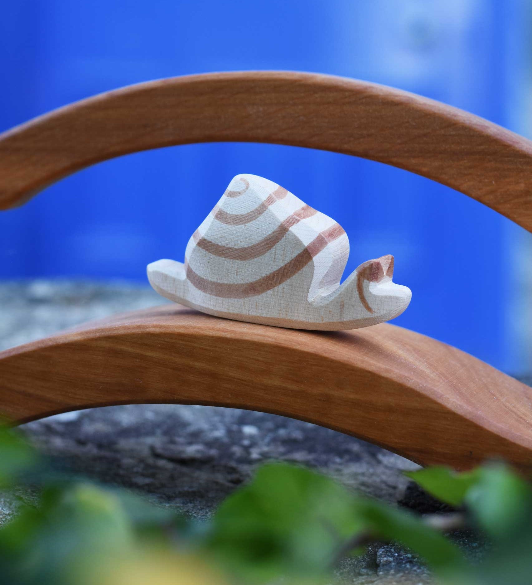 A close up of the Ostheimer snail figure on a wooden bridge. The wooden snail figure has a cream white coloured base with brown detailing.