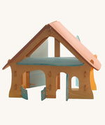Ostheimer wooden farm house toy with light red roof and light blue doors on a plain background. 