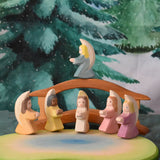 A festive scene featuring Ostheimer little angels in 6 different colours placed around the Ostheimer pond scene. The Ostheimer wooden bridge with railing can be seen in the background with a Wonderie WonderCloth with the Christmas tree design hung up on the wall behind. These wooden figures are part of a wide range of expertly hand crafted wooden toys available here at Babipur. 
