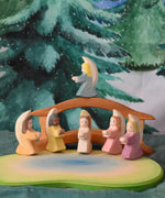 A festive scene featuring Ostheimer little angels in 6 different colours placed around the Ostheimer pond scene. The Ostheimer wooden bridge with railing can be seen in the background with a Wonderie WonderCloth with the Christmas tree design hung up on the wall behind. These wooden figures are part of a wide range of expertly hand crafted wooden toys available here at Babipur. 