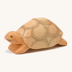 A wooden Ostheimer turtle on a cream background.