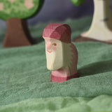 An Ostheimer violet dwarf wooden toy figure placed in a small world play scene. The dwarf figure has a violet coloured outfit with matching hat and a white beard. The figure has been placed on a green coloured Ostheimer play scarf. These wooden figures are part of a large range of expertly hand crafted, Waldorf inspired, wooden toys here at Babipur.
