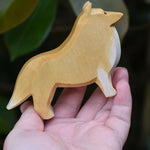 An Ostheimer Collie Dog Handmade Wooden Toy in an adults hand. These wooden figures are part of a large range of expertly hand crafted, Waldorf inspired, wooden toys here at Babipur.