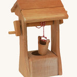 Ostheimer kids wooden water well toy with roof on a cream background.