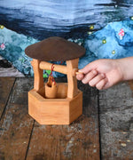 A child's hand winding up the bucket on the Ostheimer wooden wishing well toy. These wooden figures are part of a wide range of expertly hand crafted wooden toys here at Babipur. 
