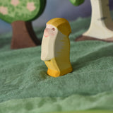 An Ostheimer yellow dwarf wooden toy figure placed in a small world play scene. The dwarf figure has a yellow coloured outfit with matching hat and a long white beard. The figure has been placed on a green coloured Ostheimer play scarf. This wooden figure is part of a large range of expertly hand crafted, Waldorf inspired, wooden toys here at Babipur. 