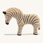 A wooden Ostheimer zebra figure on a cream background.