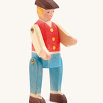 A wooden Ostheimer rider figure wearing a red waistcoat, blue trousers and a brown hat on a cream background.
