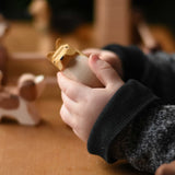 A close up of the Ostheimer collie dog's face wooden toy figure in a child's hand.  These wooden figures are part of a wide range of expertly hand crafted wooden toys here at Babipur. 