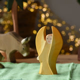 Ostheimer yellow guardian angel wooden toy figure placed on a green cotton cloth in a small world play scene. 