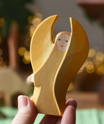 Ostheimer yellow guardian angel wooden toy figure in an adult's hand.