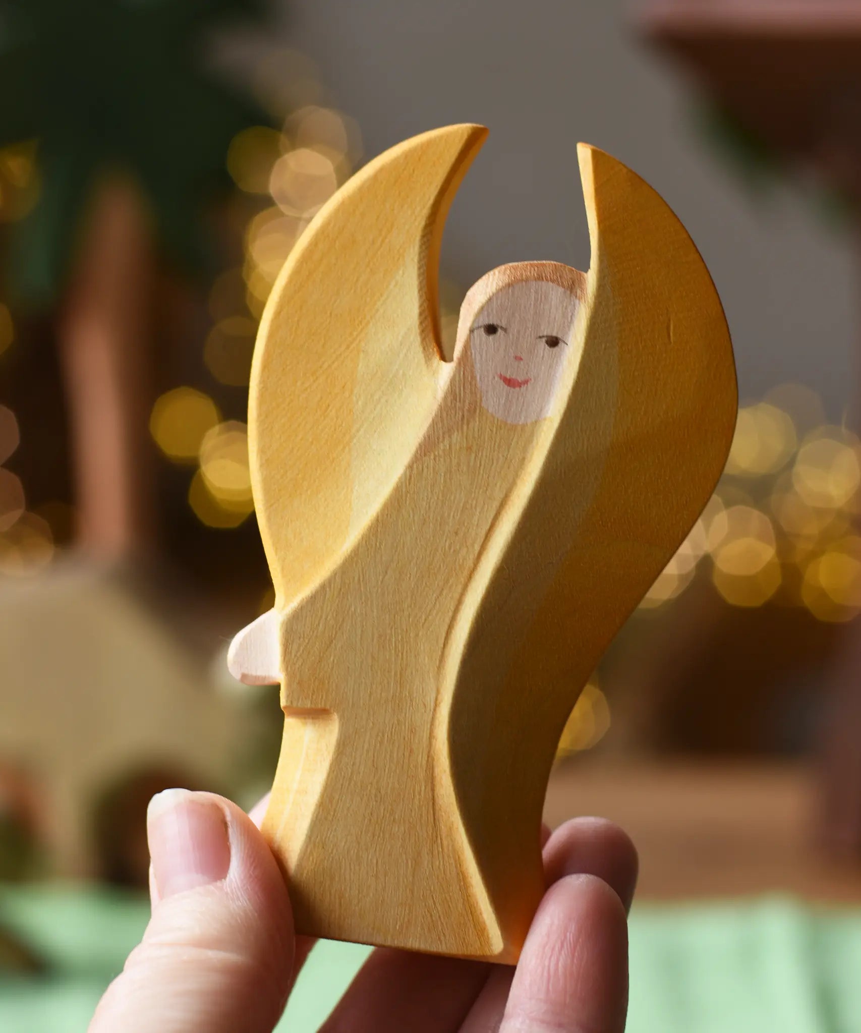 Ostheimer yellow guardian angel wooden toy figure in an adult's hand.