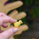 A yellow coloured Ostheimer chick shown in an adult's hand for scale. This teeny chick is part of a large range of expertly hand crafted wooden animals here at babipur.