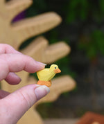 A yellow coloured Ostheimer chick shown in an adult's hand for scale. This teeny chick is part of a large range of expertly hand crafted wooden animals here at babipur.