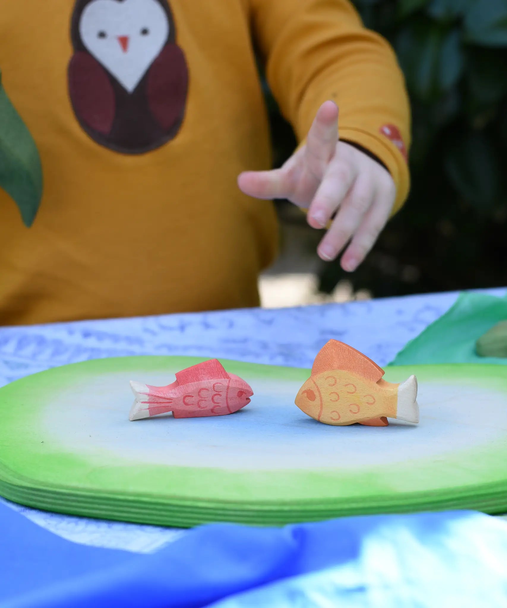 Ostheimer red and yellow handmade wooden toy figures placed on pond piece. 
