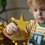 Ostheimer yellow star wooden decoration in a child's hand. 