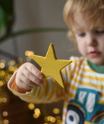 Ostheimer yellow star wooden decoration in a child's hand. 