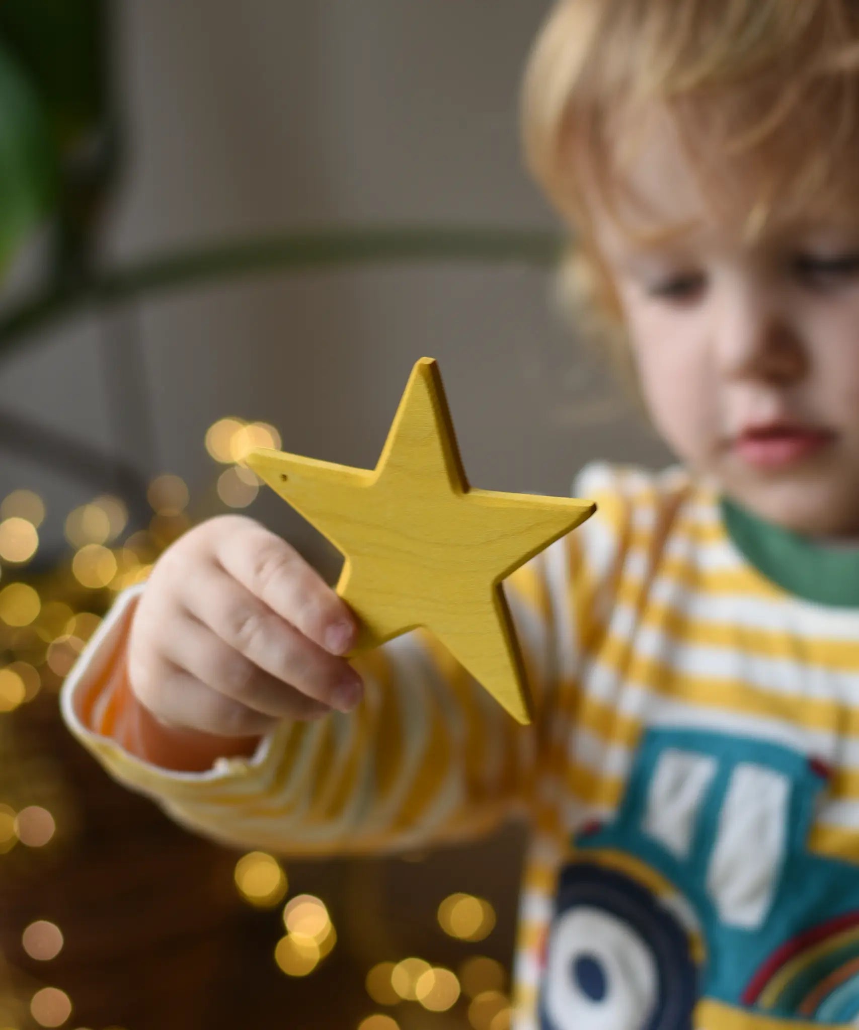 Ostheimer yellow star wooden decoration in a child's hand. 
