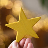 Ostheimer yellow star wooden decoration in an adult's hand. 
