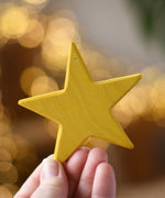 Ostheimer yellow star wooden decoration in an adult's hand. 