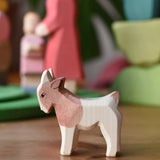 Ostheimer small standing brown and white goat wooden toy figure at the front of a play scene with other figures in the background. 