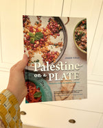 The hardcover cookbook 'Palestine on a Plate' by chef and activist Joudie Kalla. The front cover features vibrant Middle Eastern mezze plates.