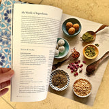 The cookbook 'Palestine on a Plate' is shown open to reveal a colourful page displaying spices and ingredients. 