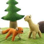 Close up of the Papoose felt fox and fawn toy figures on a green play mat in front of a Papoose tree