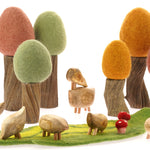 Papoose plastic-free wooden pebble animals on a green Papoose play mat in front of some wooden tree toys