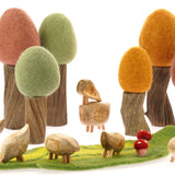 Papoose plastic-free wooden pebble animals on a green Papoose play mat in front of some wooden tree toys