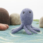 Close up of the Papoose purple octopus figure on a blue play mat in front of some Papoose rocks