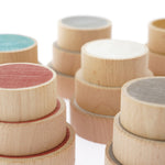 Close up of the Papoose handmade coloured wooden earth coins stacked in towers on a white background