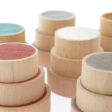 Close up of the Papoose handmade coloured wooden earth coins stacked in towers on a white background