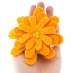 Close up of a Papoose plastic-free felt flower toy in the palm of a hand on a white background