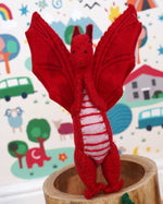 A close up of a Papoose red felted dragon in a playroom showing the stitching detail and facial features.