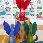A blue, green and red dragon standing in a playroom 