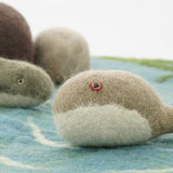 Close up of the Papoose felt fish and dolphin toys on a blue play mat in front of some Papoose rocks