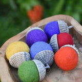 Papoose Toys felt acorns placed in a wooden dish.